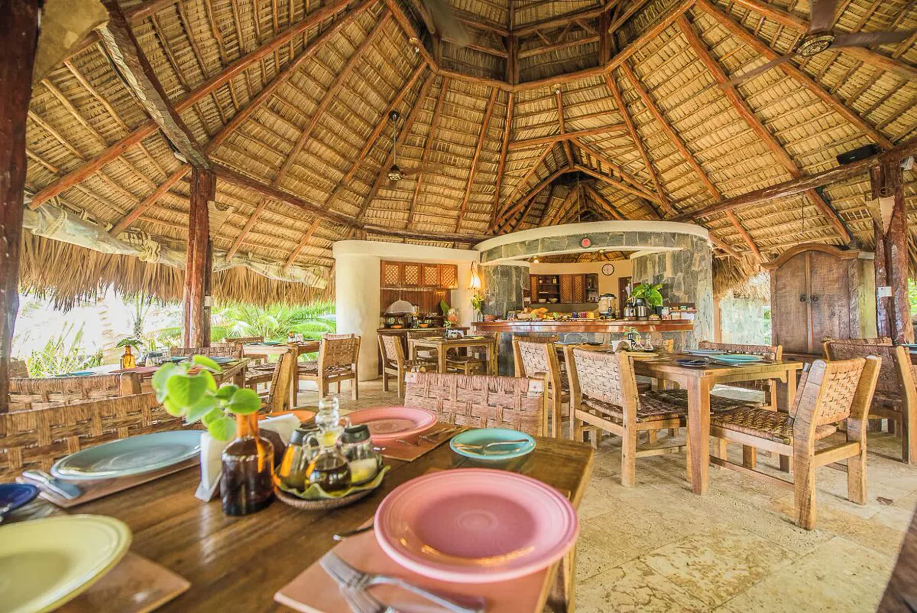 Open-air palapa restaurant with set wooden tables