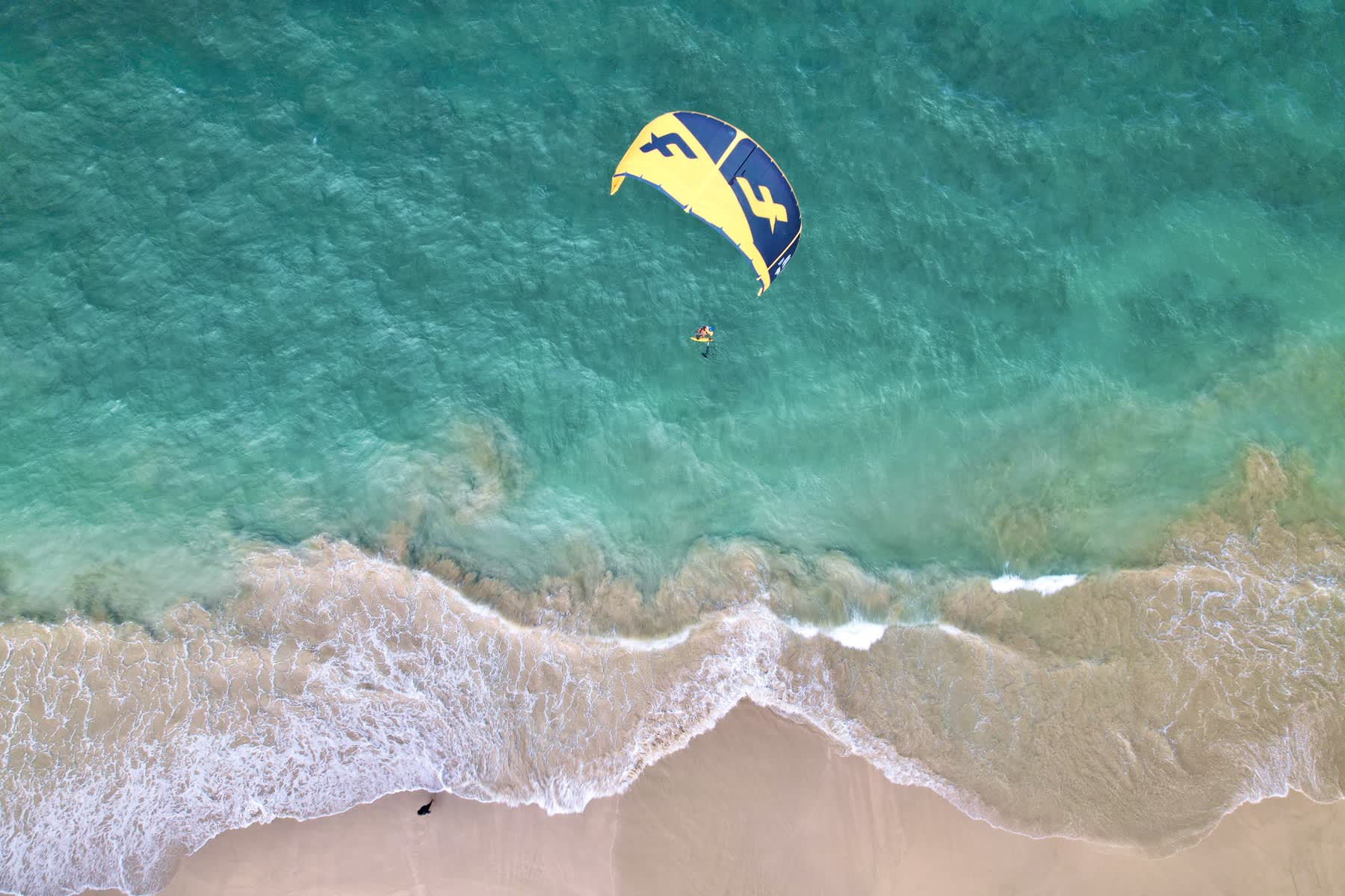 Kitesurfer from above in turquoise water at the beach